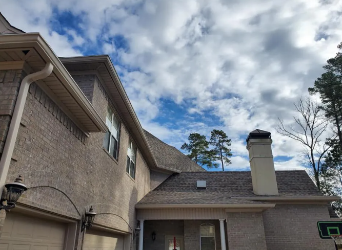 Suburban house exterior with brick walls, chimney, and a partly cloudy sky