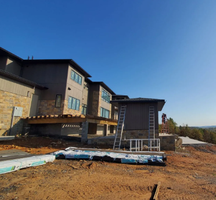 Construction site with modern houses, exposed dirt, blue sky, and scaffolding in front