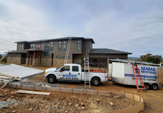 Construction site with a two-story house, white work truck, and ladder under an overcast sky