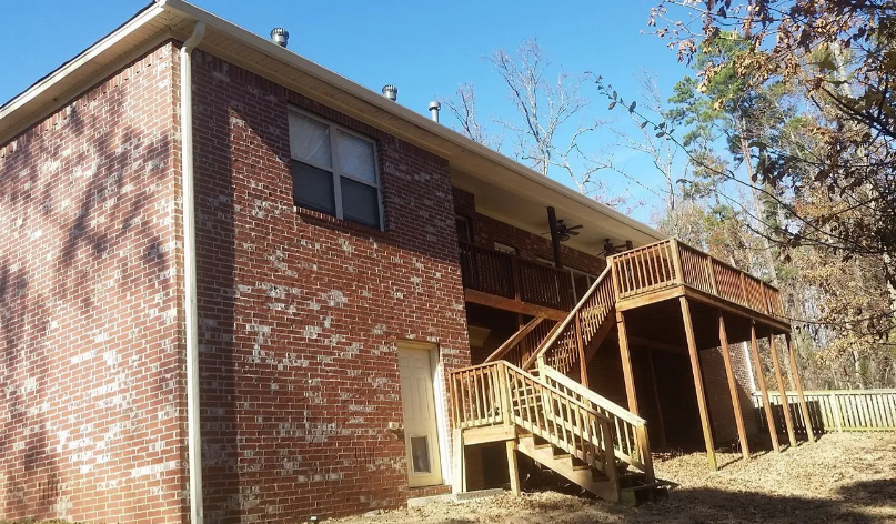 Brick apartment building with exterior wooden stairs and balconies under a blue sky