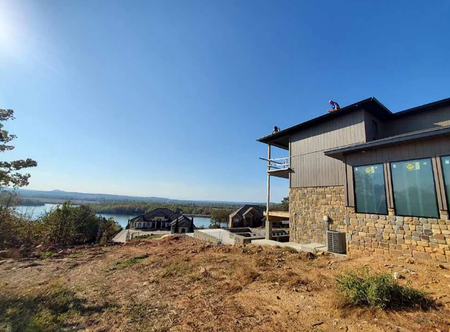Stone house on a hillside overlooking a lake under a clear blue sky