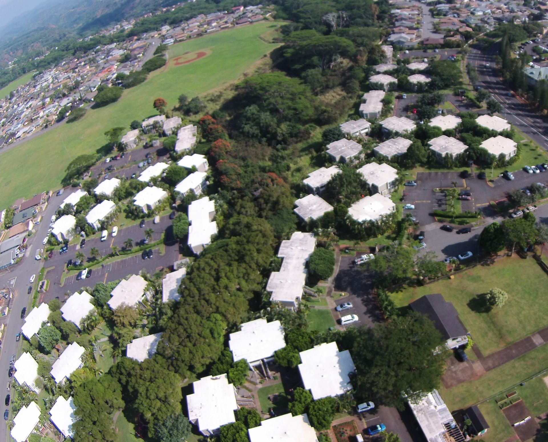 Aerial view of a complex with white, hexagonal-shaped buildings, trees, and green lawns.