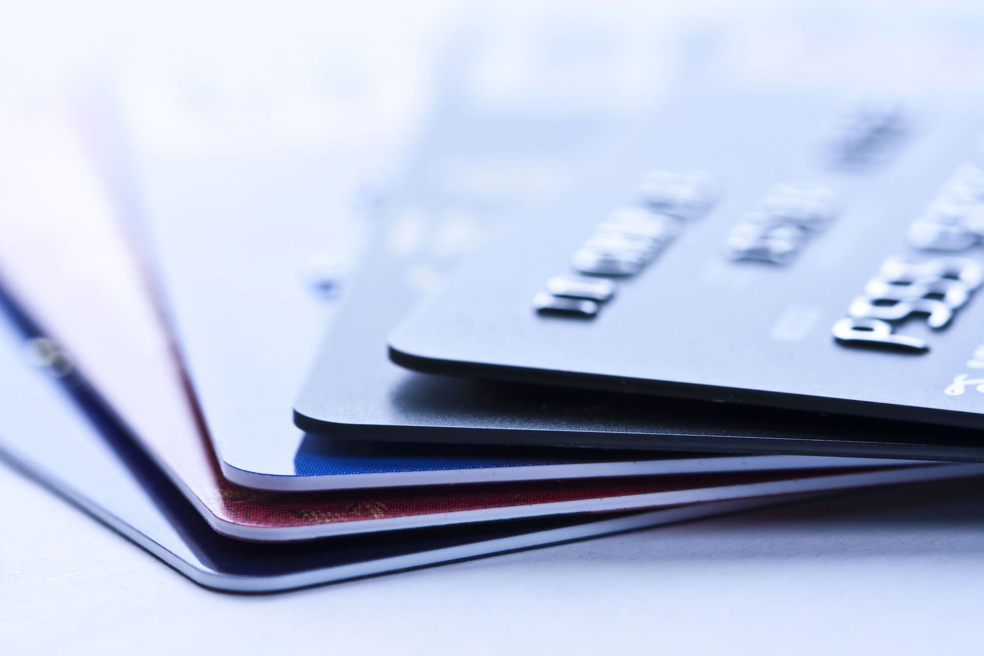 A close-up stack of several credit cards of different colors, including black, red, and blue, viewed at an angle.