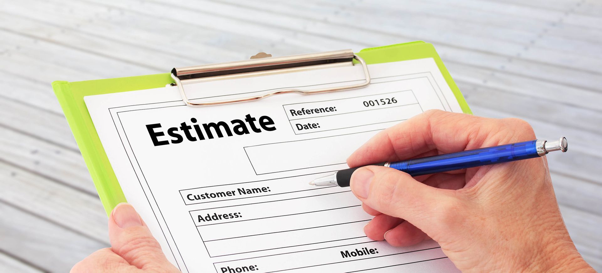 A person holding a green clipboard and writing on an estimate form with a blue pen.