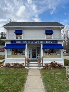 A charming white two-story store with vibrant blue awnings, a welcoming entrance, and a quaint, inviting atmosphere.
