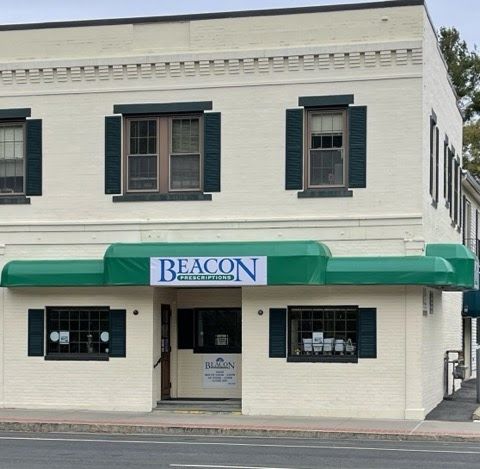 Two-story white brick building with a green awning. Black shutters on windows, creating a small-town, welcoming feel.
