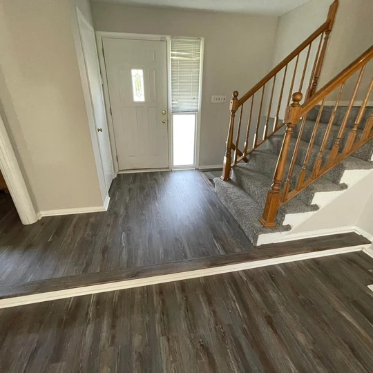 A hallway with hardwood floors and stairs in a house.