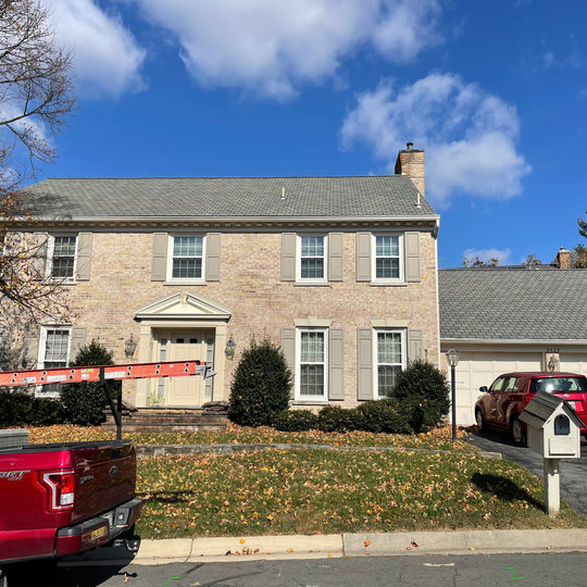A red truck is parked in front of a large brick house.