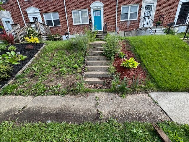 A brick house with a blue door and stairs leading up to it.