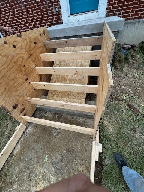 A wooden staircase is being built in front of a brick building.