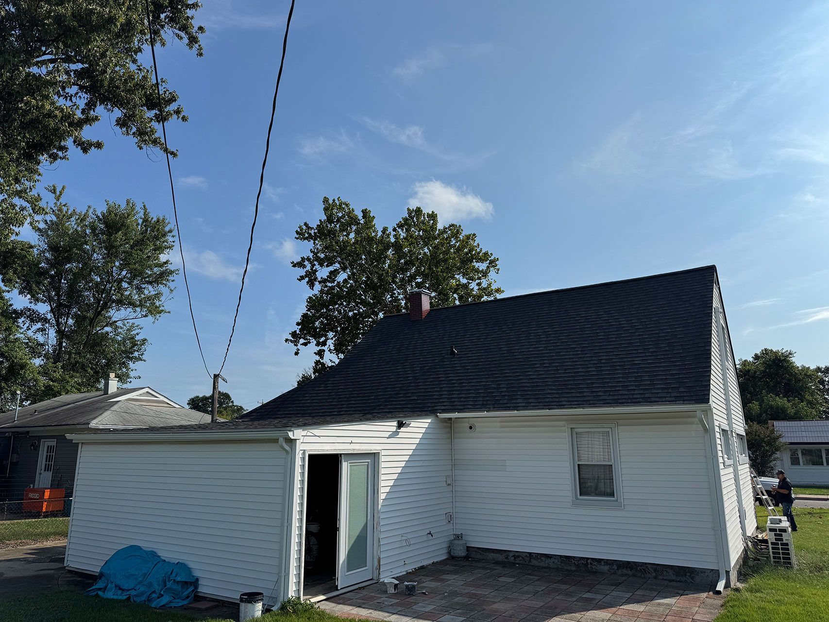 White house with dark roof against a blue sky, power lines overhead.