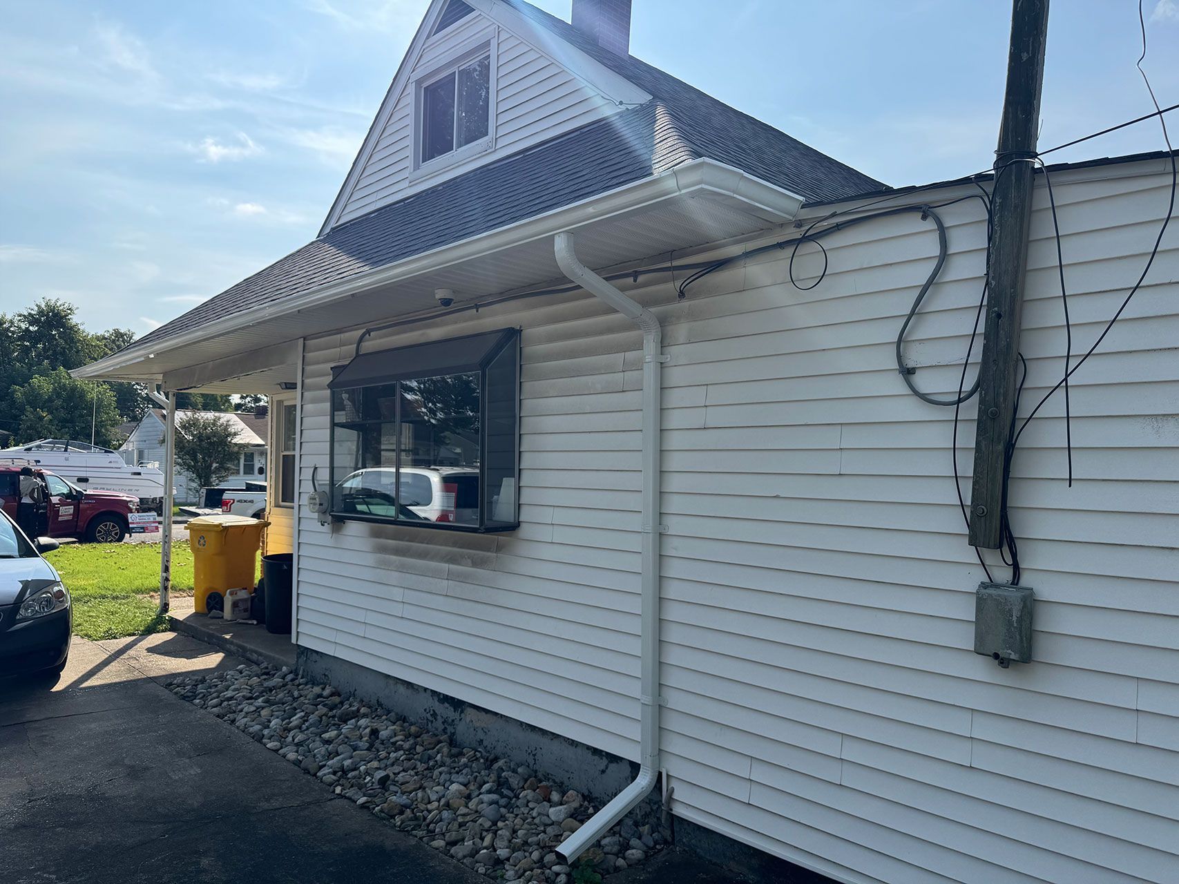 White building with drive-up window, white siding, black window frame, and gray roof.