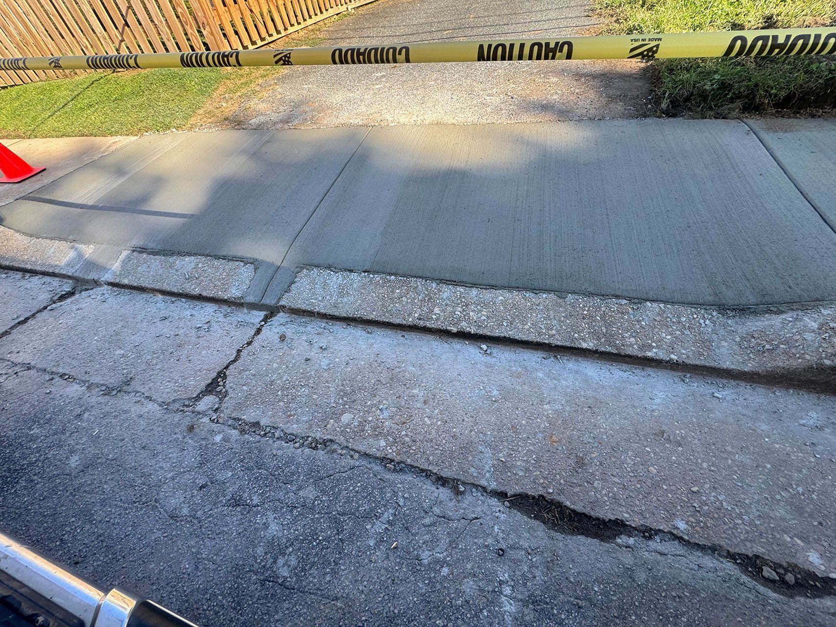 Uneven concrete sidewalk with cracks and caution tape.
