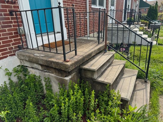 A set of stairs leading up to a brick house with a wrought iron railing.