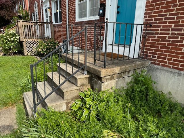 A brick house with a blue door and stairs leading up to it.