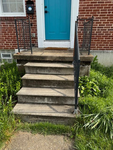 A set of stairs leading up to a blue door of a brick house.