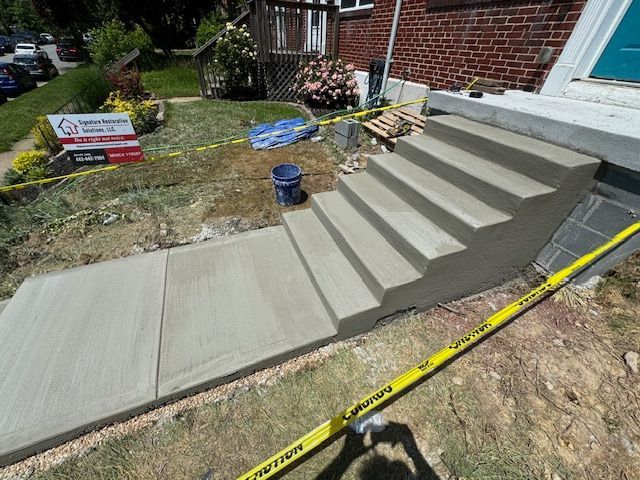 A concrete staircase is being built in front of a brick house