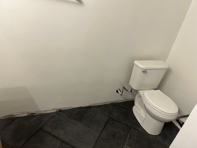 A toilet is sitting in a bathroom next to a wall.