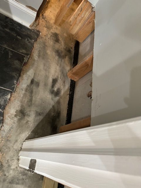 There is a hole in the floor in the corner of a room.