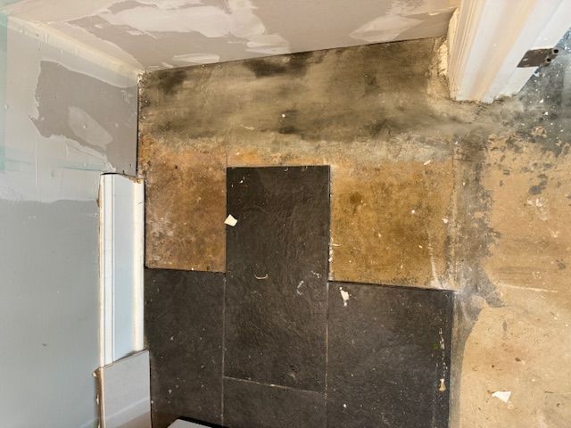 A bathroom with a tiled floor and a dirty wall.
