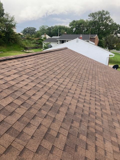 A brown roof with a white house in the background