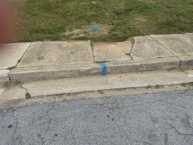 A sidewalk with a blue tape marking the edge of it.