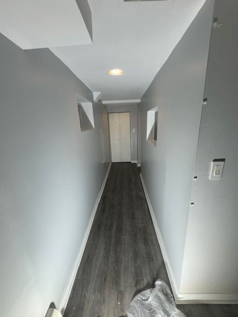 A long hallway with a wooden floor and white walls