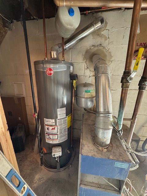 A water heater is sitting next to a boiler in a basement.