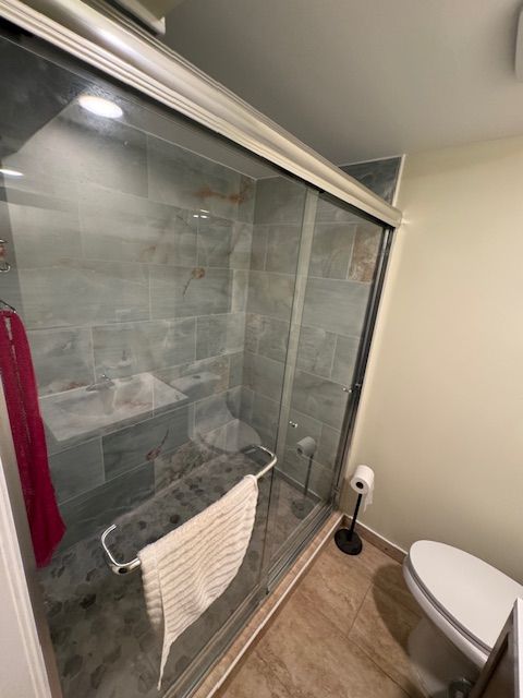 A bathroom with a toilet and a shower with a glass door
