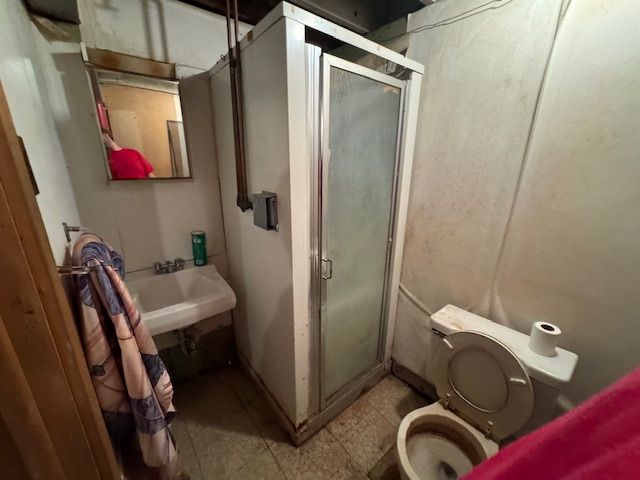 A bathroom with a toilet , sink and shower.