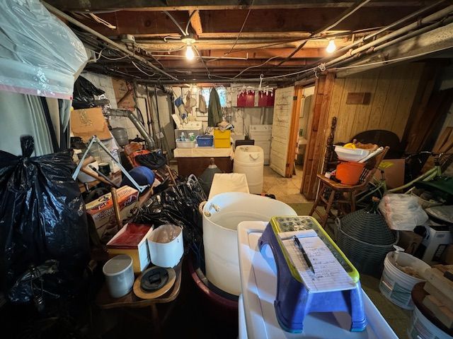 A basement filled with lots of junk and a stool.