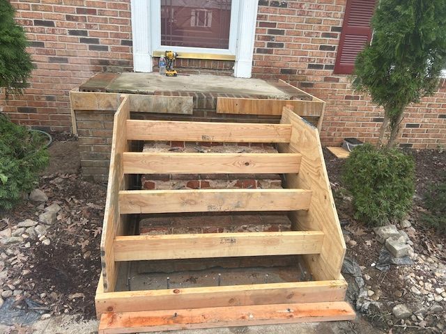 A staircase is being built in front of a brick house