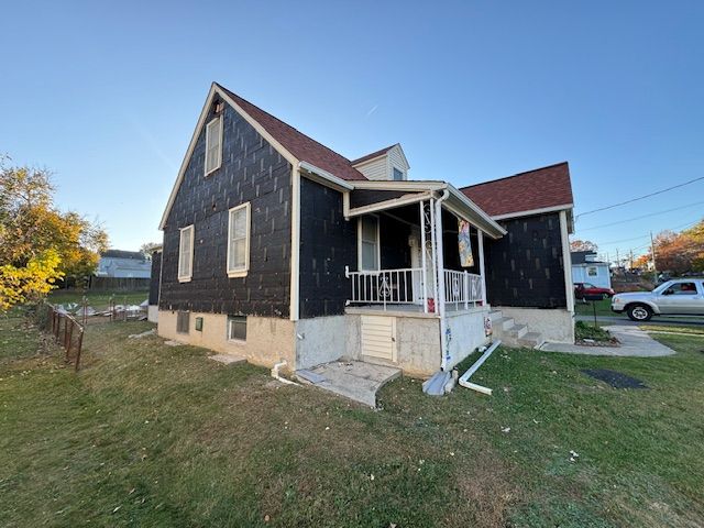 A black house with a red roof and a white truck parked in front of it.