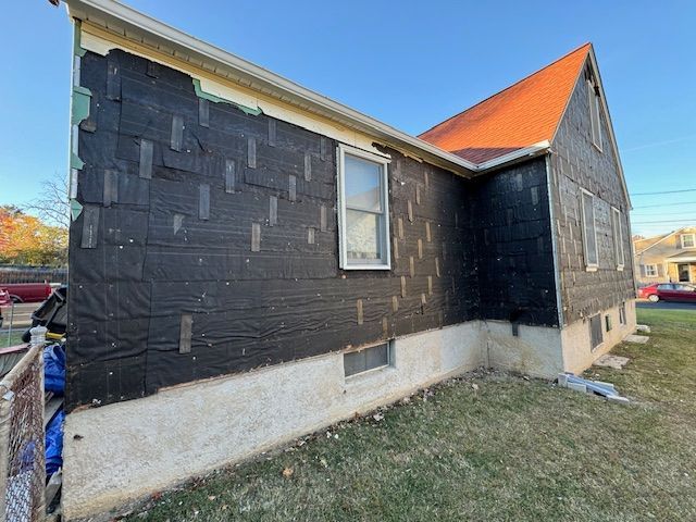 The side of a house is being painted black.