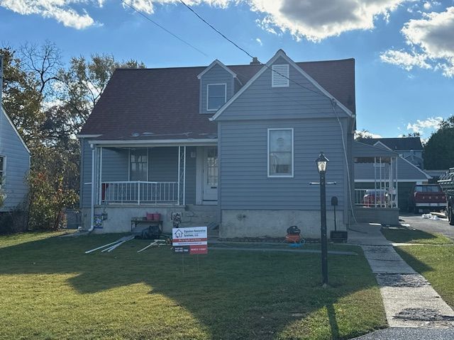 A gray house with a red roof is for sale