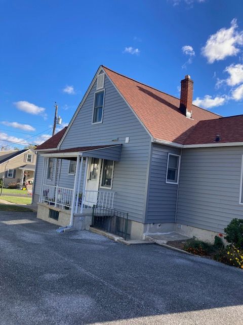 A gray house with a red roof and a porch