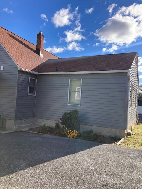 A gray house with a red roof and a driveway