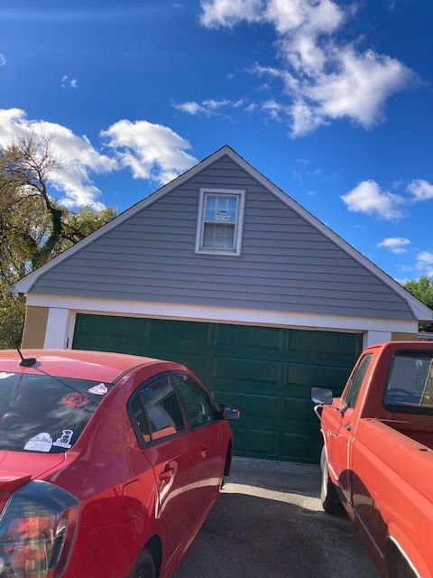A red car is parked in front of a garage