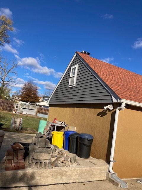 A house with a red roof is surrounded by trash cans