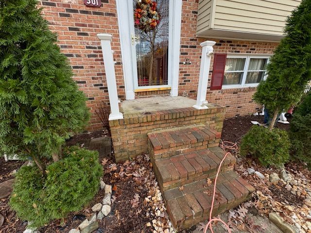 A brick house with stairs leading up to the front door