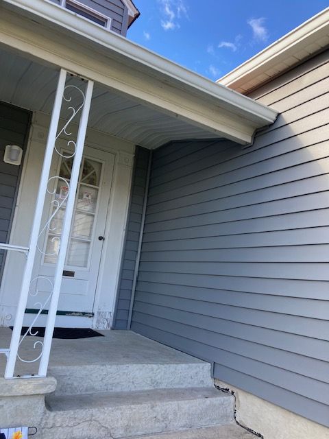 A gray house with a white porch and stairs