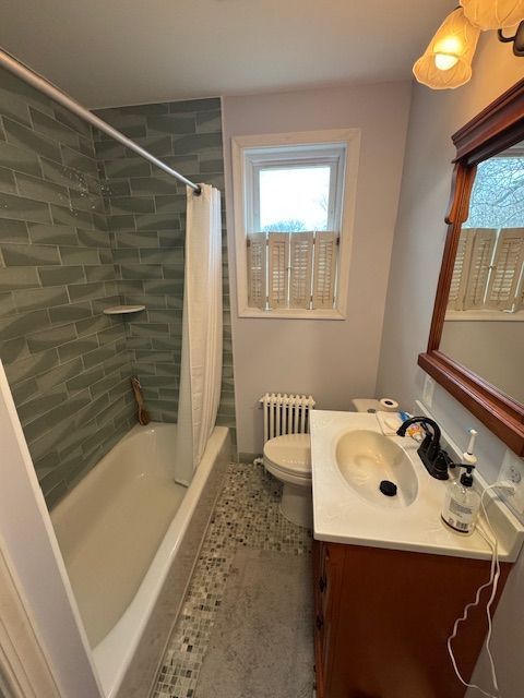 A bathroom with a sink , toilet , tub and mirror