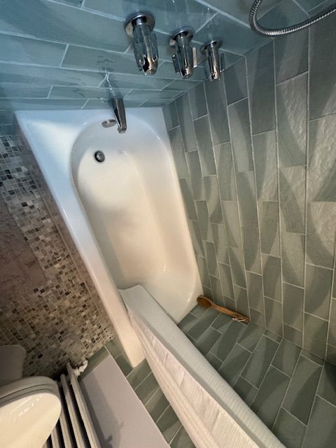 A bathroom with a bathtub , toilet and shower.