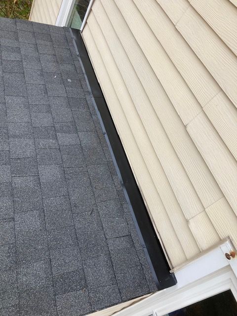 A house with a black roof and a white siding