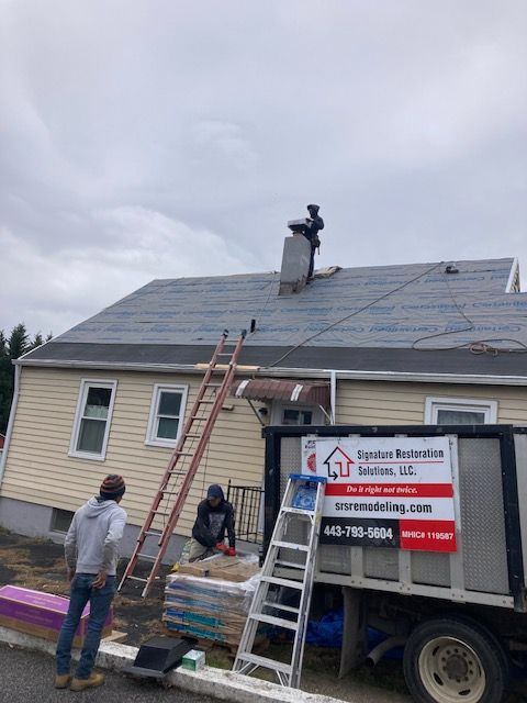 Roofing team is working on the roof of a house next to a truck