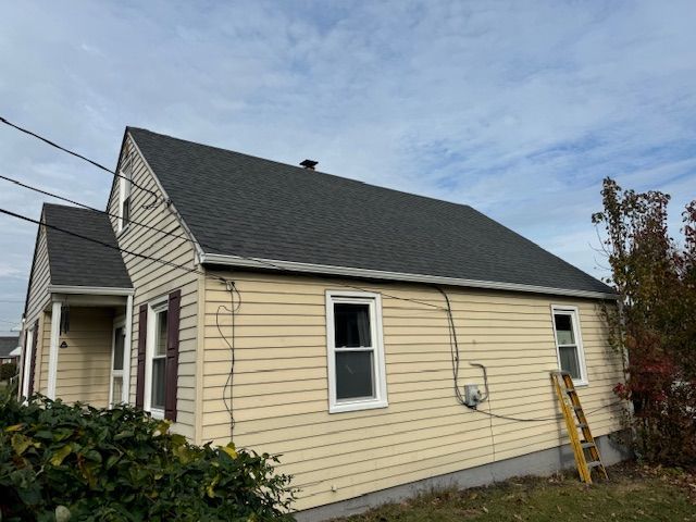 A house with a black roof and a ladder on its exterior wall