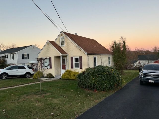 A house with a new roof and two vehicles parked on its sides