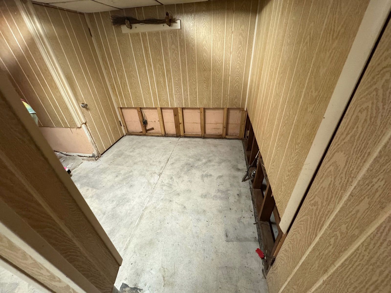 A damaged room with a concrete floor and wooden walls