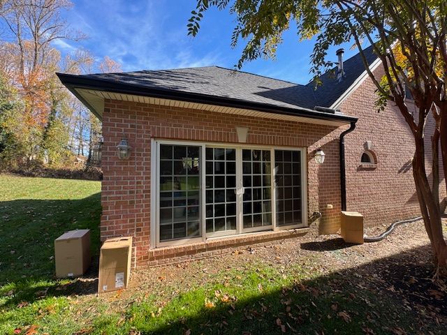 Brick building with sliding glass doors, black roof, and two boxes on the ground.
