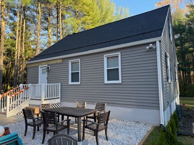 Gray house with black roof, white trim, and outdoor dining set.